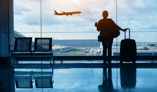 Woman with suitcase looking out window at an airplane mid flight