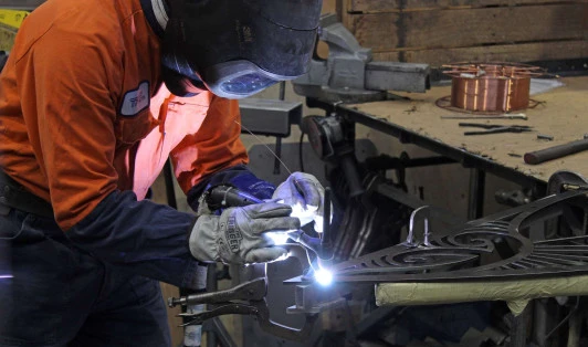 Man in hi-vis safety gear using welding machine in workshop