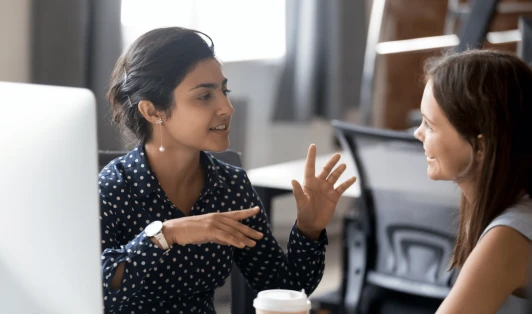 Two women talking to each other in an office.