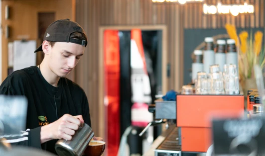 Cafe worker pouring a coffee.