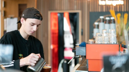 Cafe worker pouring a coffee.
