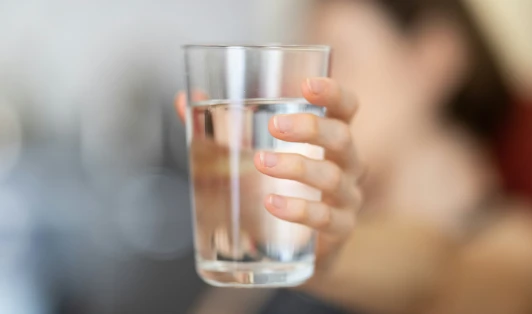 A hand holds a glass of water.