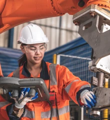 A woman in high-vis clothing and hard hat operates machinary.