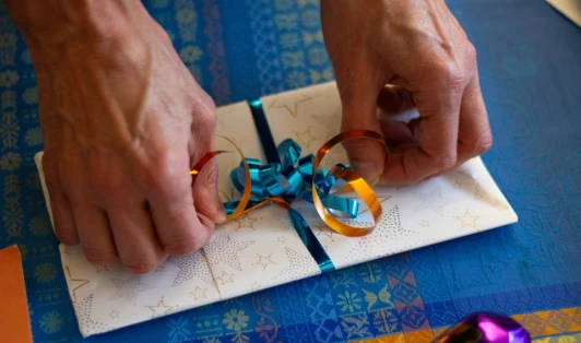 Two hands tie a ribbon around a gift.