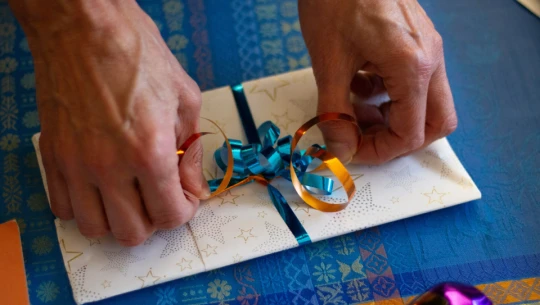 Two hands tie a ribbon around a gift.
