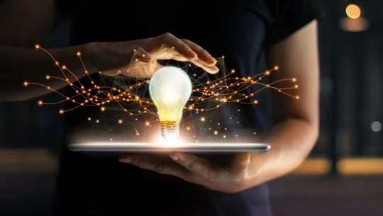 Light bulb which is lit with someone holding their hand over the top of it