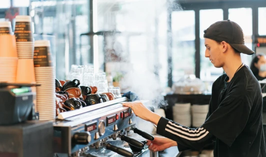Cafe worker operates a coffee machine.