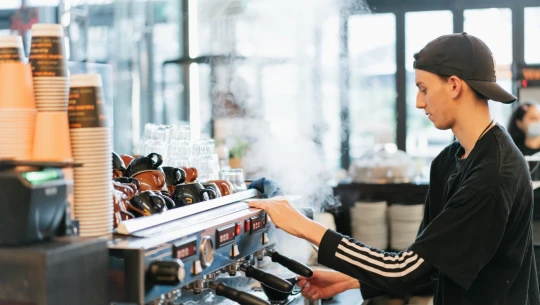 Cafe worker operates a coffee machine.