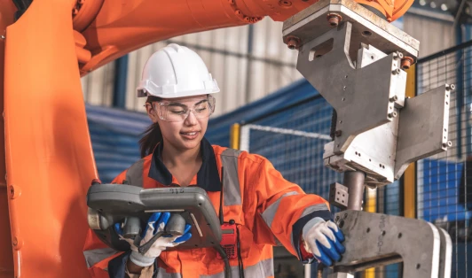 A worker dressed in high-vis gear and hard hat operating machinary.