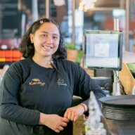 A cafe worker leans against a counter.