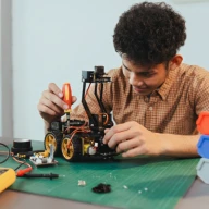 A technician builds a robotic model at a workstation.