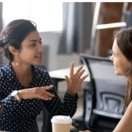 Two women talk in an office.