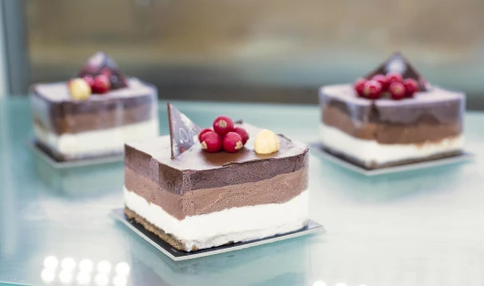 Close up of 3 pieces of square cakes on glass tabletop